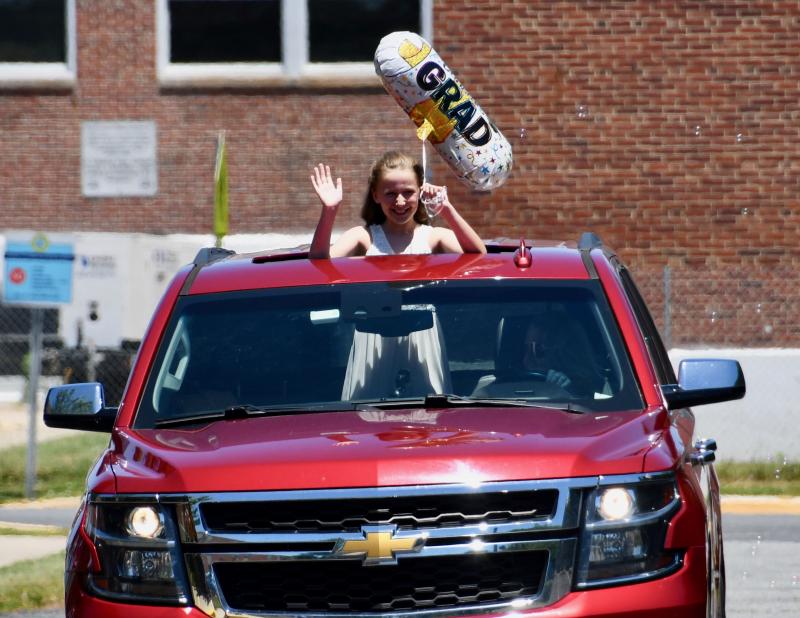 With a graduation balloon and a wave, Shields Elementary student Sasha Robbins takes part in the parade. RON MACARTHUR PHOTO